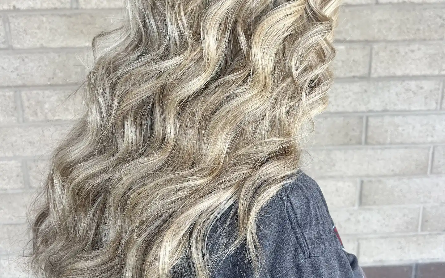 Long wavy blonde hair with bright balayage, color done on the Entourage clinic floor