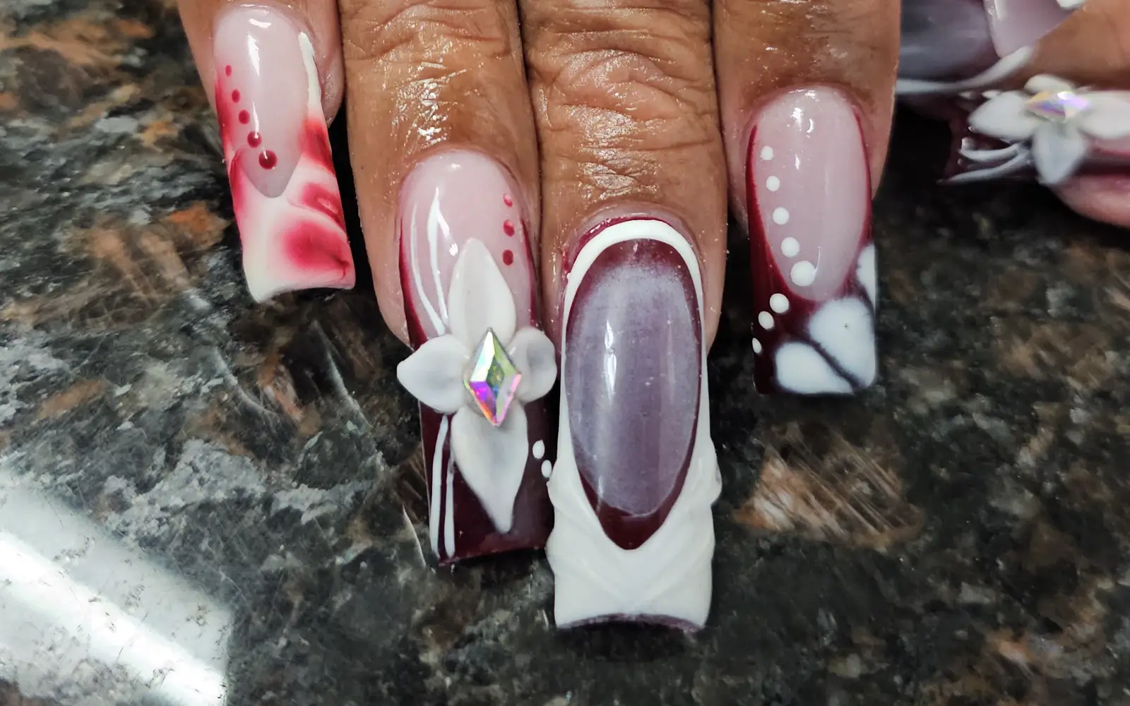 Hand-painted burgundy and white floral nail art with a 3D flower on long square nails